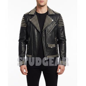May include: Black leather jacket with silver-tone stud embellishments. The jacket features a classic biker style with a notched collar, asymmetrical zipper, and multiple pockets. Studs are placed on the shoulders, collar, and cuffs. The jacket is a classic piece of outerwear.