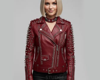 May include: A burgundy leather jacket with silver metal studs and zippers. The jacket has a classic biker style with a notched collar, asymmetrical zipper closure, and a belt at the waist. The sleeves and shoulders are heavily studded.