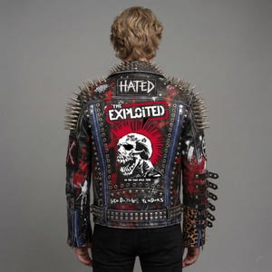 May include: A black leather jacket featuring silver metal spikes on the shoulders and back. The back displays a large graphic of a skull with a red mohawk, the text THE EXPLOITED, HATED, and SICK ON THE BUS TENDONS, with leopard print accents.