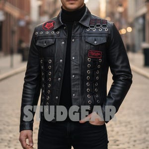 May include: Black leather jacket with a classic collar, two chest pockets, and decorative grommets. The jacket features red patches and the word "STUDGEAR" across the front. The jacket has a lace-up design on the sides.