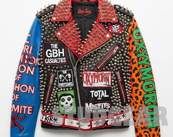 Puede incluir: Chaqueta de cuero negra con tachuelas plateadas, detalles rojos y negros y parches. La chaqueta presenta una manga azul con texto blanco y una manga naranja con estampado de leopardo y texto verde. Cuello rojo con púas plateadas.
