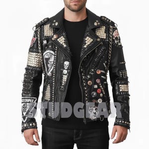 May include: Black leather jacket with silver studs, spikes, and patches. The jacket features a classic biker style with a notched collar, asymmetrical zipper, and multiple pockets. Patches include skulls and the text "ICE COOPER".