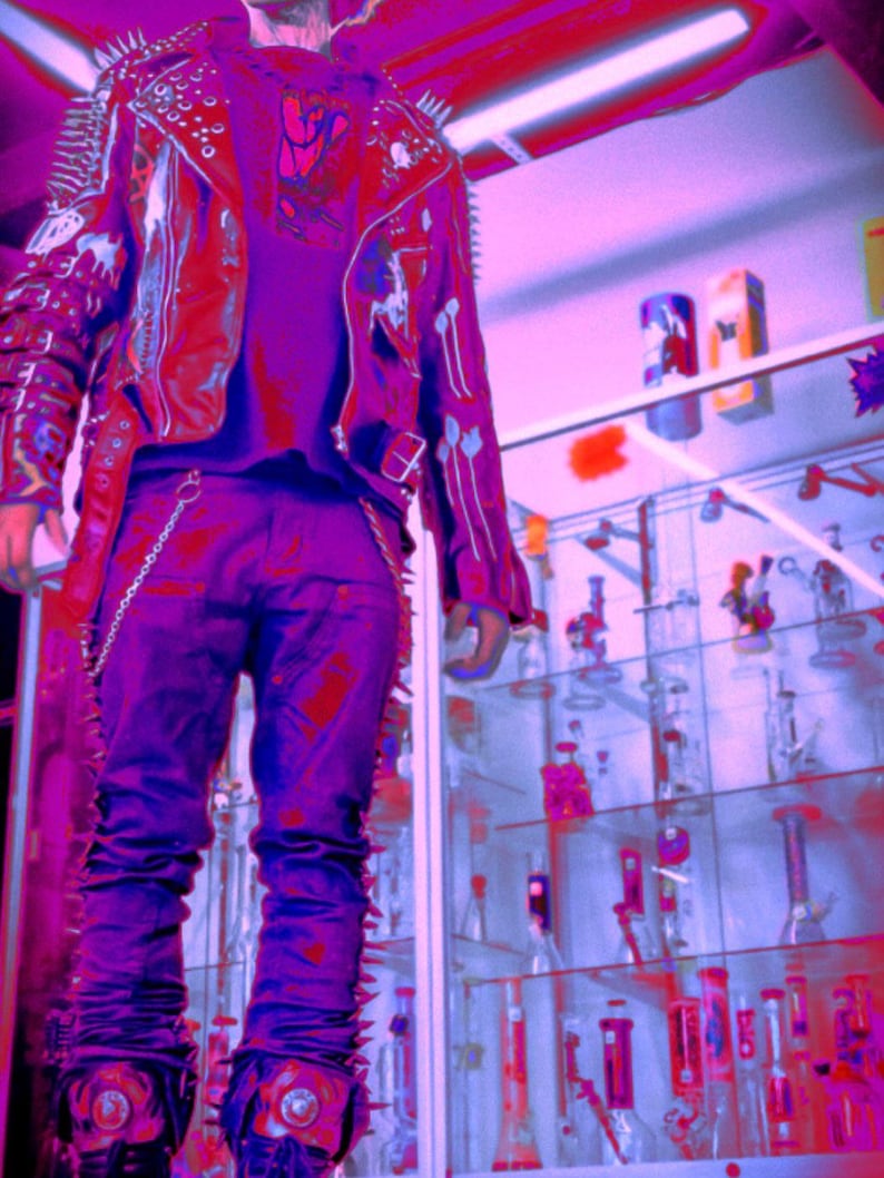 May include: A leather jacket featuring metal spikes on the shoulders and sleeves, paired with dark trousers. The jacket is adorned with white painted graphics and a silver chain attached to the waistband. The overall colour palette is heavily saturated in shades of purple and red.