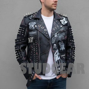 May include: Black leather jacket with silver spikes, patches, and decorative rivets. The jacket features a Route 66 patch, skull and crossbones, and other graphic designs. The jacket has a distressed look with red accents and a zipper closure.