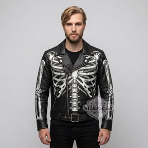 May include: Black leather jacket with a white skeleton design. The jacket has a classic biker style with a notched collar, zip closure, and a belt at the waist. The skeleton design is printed on the front and sleeves.