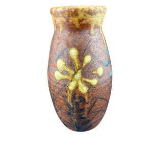 May include: A brown ceramic vase with a textured surface and a wide opening. The vase features a yellow floral design in the center, with accents of red, blue, and black. The vase is approximately 7 inches tall.