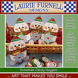 May include: A set of four snowman candy huggers, each with a red and white scarf, green hat, and a snowflake with a heart in the center. The snowmen are holding small candy bars in their hands. The snowmen are sitting in a wicker basket. The text "Snowman Candy Huggers" is printed below the image. The text "... ART THAT MAKES YOU SMILE ..." is printed below the text "Snowman Candy Huggers".