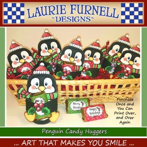 May include: A basket filled with penguin-shaped candy huggers, each holding a small wrapped candy bar. The penguins are painted in black and white with red and green accents. The candy bars are wrapped in red and green paper with festive holiday greetings. The text on the candy wrappers reads "Merry Christmas" and "Happy Holidays".