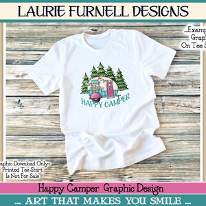 May include: A white t-shirt with a graphic design of a teal camper with pink wheels, surrounded by green trees. The text "HAPPY CAMPER" is printed below the camper. The t-shirt is on a wooden background.