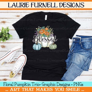 May include: Black t-shirt with a graphic design of three pumpkins with floral accents and the word "Blessed".