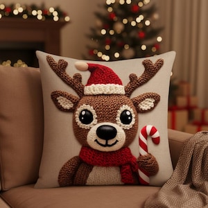 Peut inclure: Un coussin de Noël décoratif avec un motif de renne tricoté. Le renne porte un bonnet de Père Noël rouge et une écharpe rouge, et tient une canne en bonbon. Le coussin est marron et beige, avec un aspect texturé.