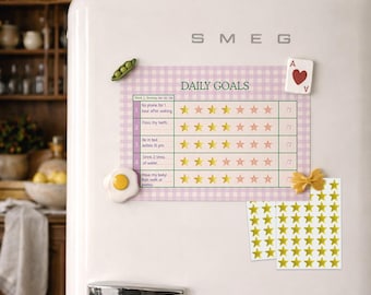 May include: A white SMEG refrigerator with a magnetic daily goals chart, star stickers, and decorative magnets. The chart has a pink gingham background and lists daily tasks with star ratings. Other magnets include a playing card and a fried egg.