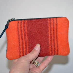 May include: A small orange and red striped zippered pouch made of wool.