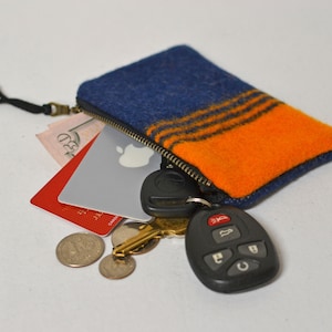May include: A blue and orange zippered pouch with a key chain and car key, credit cards, and coins inside.