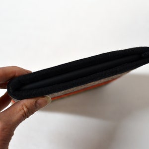 May include: A black and brown fabric case with a zipper closure. The case is folded in half and has a textured fabric exterior.