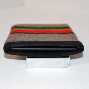 May include: A black felt case with a colorful striped pattern. The case is folded closed and sitting on a white surface.