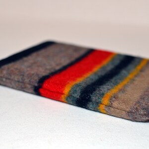 May include: A brown, gray, red, yellow, and blue striped fabric pouch. The pouch is folded in half and the fabric is fuzzy.