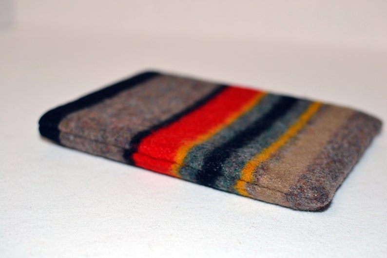 May include: A brown, gray, red, yellow, and blue striped fabric pouch. The pouch is folded in half and the fabric is fuzzy.