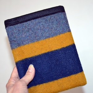 May include: A striped fabric pouch with a black trim. The pouch has blue, yellow, and dark blue stripes.