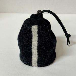 May include: A dark charcoal gray felt drawstring pouch featuring a vertical light gray stripe down the center. The pouch is secured at the top with a black cord and a plastic toggle closure, creating a gathered opening for storage and organization.