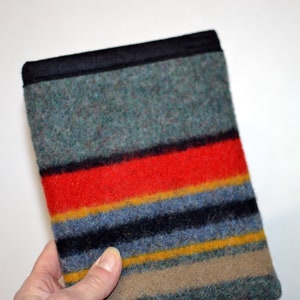 May include: A striped fabric pouch with a black border. The fabric is a mix of green, red, yellow, blue, and brown.