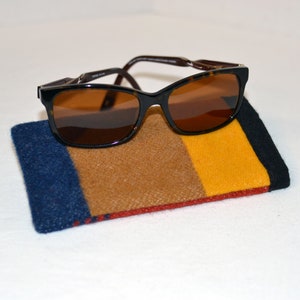 May include: Brown sunglasses with brown lenses in a striped fabric case with blue, brown, yellow, and red stripes.