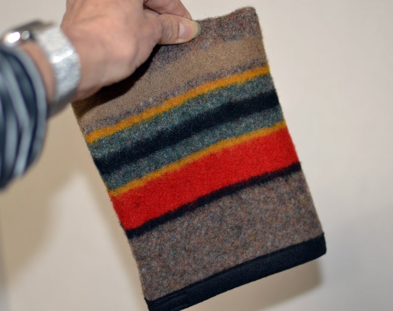 May include: A multi-colored striped wool blanket with a black border. The blanket is made of a thick, soft material and has a rustic look.