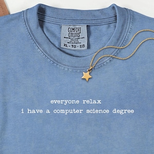 Könnte beinhalten: Hellblaues Comfort Colors T-Shirt mit dem weißen Text "everyone relax i have a computer science degree". Eine goldene Stern-Anhänger-Halskette liegt auf dem Shirt. Das Shirt hat einen Rundhalsausschnitt und ein Etikett mit der Aufschrift XL-TG-EG.