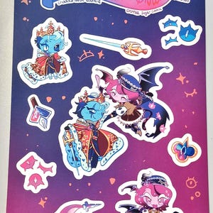 Puede incluir: Una hoja de pegatinas con personajes de dibujos animados con atuendos reales. Las pegatinas representan personajes con piel azul y rosa, que llevan coronas y capas. El fondo es un degradado de púrpura y rosa con acentos en forma de estrella y ojo. El texto en la hoja dice "A Script Written in Fated Discord."