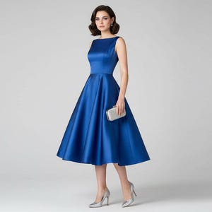 Peut inclure: Robe de soir&eacute;e bleu roi en satin, sans manches, avec un col bateau et une jupe &eacute;vas&eacute;e. La robe est port&eacute;e avec des talons argent&eacute;s et une pochette assortie. Une tenue &eacute;l&eacute;gante pour les &eacute;v&eacute;nements formels.