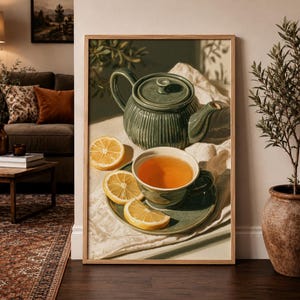 Puede incluir: Una lámina de arte enmarcada que muestra una tetera estriada de color verde oscuro y una taza a juego sobre un platillo. La taza contiene té ámbar y tres rodajas de limón amarillo brillante están dispuestas sobre un paño blanco junto al juego.