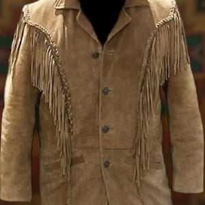 Könnte beinhalten: Hellbraune Wildlederjacke mit Fransen an Schultern und Ärmeln. Die Jacke hat eine Knopfleiste, ein fallendes Revers und zwei Vordertaschen. Die Jacke ist im klassischen Western-Stil gehalten.