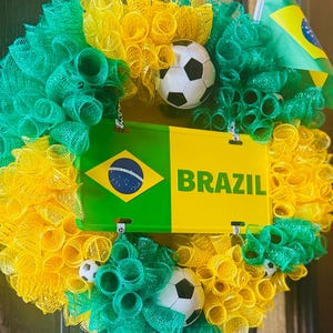Puede incluir: Una vibrante corona con los colores de la bandera brasile&ntilde;a, con malla verde, amarilla y blanca. Incluye una placa de matr&iacute;cula con "BRAZIL" y una bandera brasile&ntilde;a, junto con balones de f&uacute;tbol. Una decoraci&oacute;n festiva.