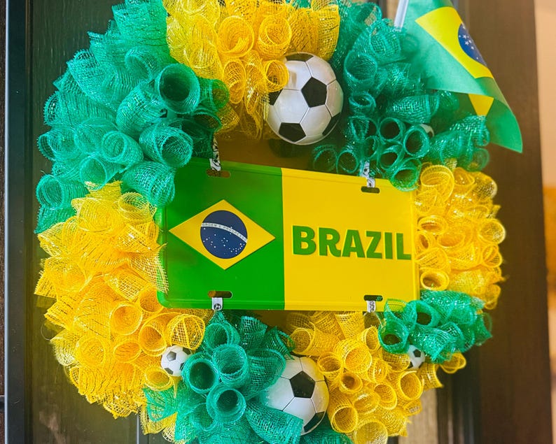 Puede incluir: Una vibrante corona con los colores de la bandera brasile&ntilde;a, con malla verde, amarilla y blanca. Incluye una placa de matr&iacute;cula con "BRAZIL" y una bandera brasile&ntilde;a, junto con balones de f&uacute;tbol. Una decoraci&oacute;n festiva.