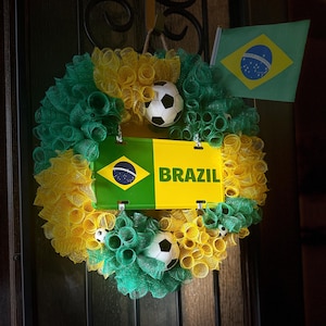 Puede incluir: Una corona decorativa con los colores de la bandera brasile&ntilde;a, con malla verde y amarilla, balones de f&uacute;tbol y un letrero que dice "BRAZIL". Tambi&eacute;n se incluye una peque&ntilde;a bandera brasile&ntilde;a.