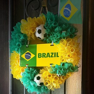 Puede incluir: Una corona decorativa con los colores de la bandera brasile&ntilde;a, con malla verde y amarilla, balones de f&uacute;tbol y un letrero que dice "BRAZIL". Tambi&eacute;n se incluye una peque&ntilde;a bandera brasile&ntilde;a.