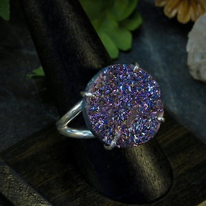 May include: A silver ring with a large, round, iridescent purple and blue druzy stone.