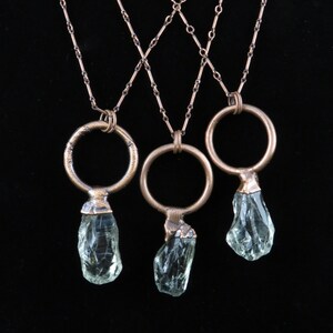May include: Three copper chain necklaces with clear crystal pendants and copper rings. The necklaces are layered and criss-crossed.
