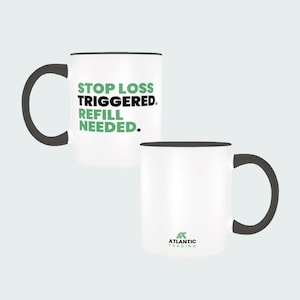 Può includere: Tazza in ceramica bianca con manico e bordo neri. La tazza presenta il testo "STOP LOSS TRIGGERED. REFILL NEEDED." in verde e nero. Il logo Atlantic Trading è sul retro della tazza.