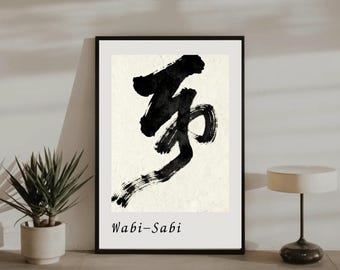 May include: Black framed art print featuring a bold, abstract calligraphy design in black ink on an off-white background. The text "Wabi-Sabi" is printed in a simple font below the artwork. The print is displayed on a neutral-toned wall.