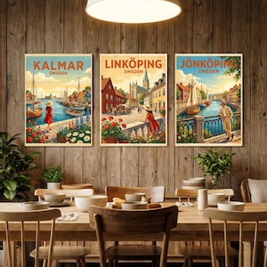 May include: Three framed travel posters with the names Kalmar, Linköping, and Jönköping, Sweden, are displayed on a wooden wall. Each poster features a vintage illustration of a city scene with boats, buildings, and people. The posters are above a wooden dining table.