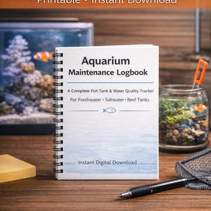 May include: A spiral-bound "Aquarium Maintenance Logbook" with the title on the cover. The cover also includes the text "A Complete Fish Tank & Water Quality Tracker For Freshwater • Saltwater • Reef Tanks". A pen, a small notepad, and a fish net are also visible.