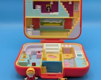 May include: A vintage red and yellow Polly Pocket playset, open to reveal a multi-level dollhouse interior. Includes a miniature doll and two animal figures. The playset features a kitchen, bathroom, and bedroom, with a blue background.
