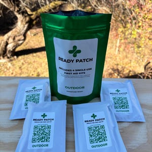 May include: A green pouch and four white packets of "READY PATCH" first aid kits. The green pouch and white packets have a white label with a green cross symbol and the word "OUTDOOR". The text "INCLUDES 4 SINGLE-USE FIRST AID KITS" is also visible.