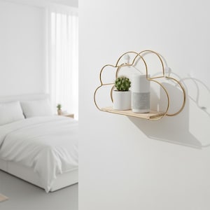 Peut inclure: Étagère en métal doré en forme de nuage avec une base en bois clair. Un petit cactus dans un pot blanc et un haut-parleur blanc et gris sont posés sur l'étagère. L'étagère est fixée sur un mur blanc.