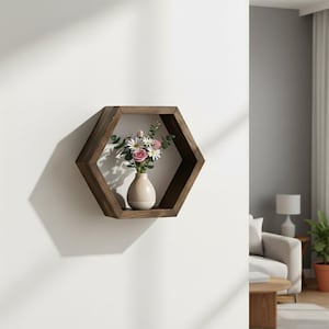 Peut inclure: Une étagère hexagonale en bois brun foncé fixée à un mur blanc. À l'intérieur de l'étagère, un petit vase crème contient un bouquet de roses roses et de marguerites blanches. L'étagère projette une ombre sur le mur.