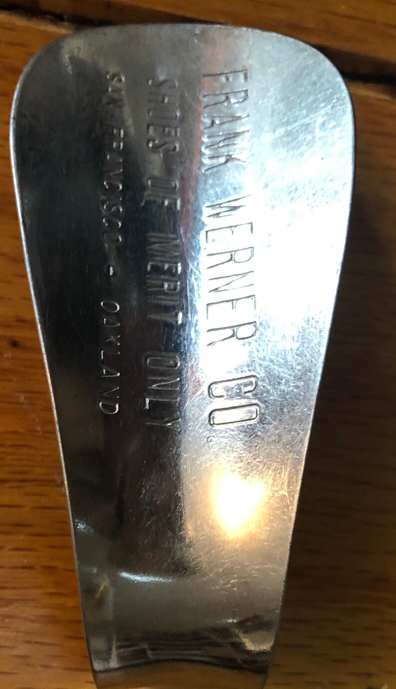 May include: A silver shoehorn with the text "FRANK WERNER CO. SALES OF MERIT ONLY. SILVERSC. - OAKLAND" engraved on the back.