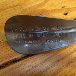 May include: A silver metal shoe horn with the text "FRANK WERNER CO. SHOES OF MERIT ONLY SAN FRANCISCO - OAKLAND" engraved on it.