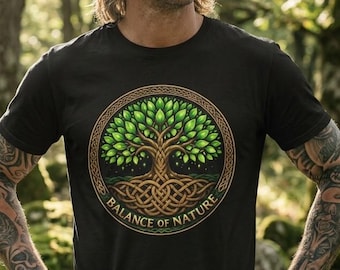 May include: A black short-sleeved t-shirt featuring a circular graphic of a tree with green leaves and brown intertwined roots. The design is enclosed in a decorative border with the text "BALANCE OF NATURE" printed in gold lettering at the bottom.