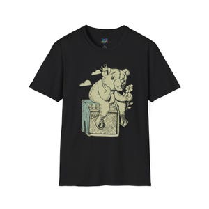 May include: Black t-shirt featuring a cartoon bear wearing a crown and holding a flower, sitting on a vintage amplifier. The amplifier has the word "Blues" on it. The shirt has the logo "Loco Pears" on the top.